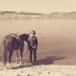Reiterin und Pferd am Seeufer